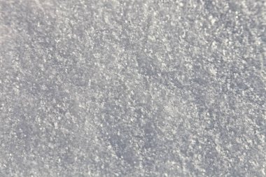 Güneşli bir kış gününde kar tanelerinin yakın çekim görüntüsüyle beyaz kar dokusu arka planı