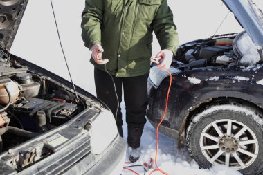 Servis elemanı açık kaputlu iki arabanın başlama kablolarıyla dışarıda duruyor. Donmuş araba motoru soğuk. Yedek akümülatörle ve kışın timsah derisi klipslerle çalışmaya başla.