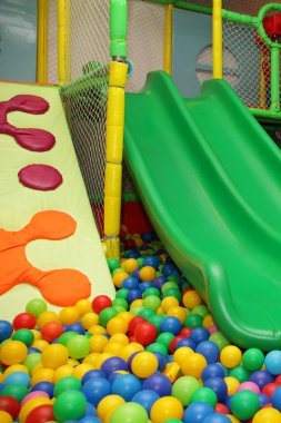 Çocuk kaydırağıyla bir sürü renkli plastik top modern kapalı okul bahçesinin iç kısımlarına yakın.