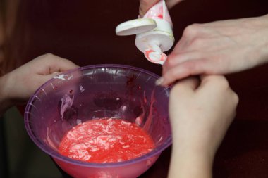 Çocukların elleri kırmızı bir balçığa renk katıyor. Kapalı çekimde, çocukların kapalı mekanlarda eğlencesine.