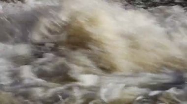 Yakın çekim üniforması güçlü köpüklü kahverengi su akıntısı hidroelektrik santralinden köpüklü, su soldan sağa akıyor.