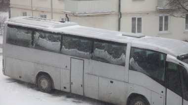 Kar, kış günü şehir avlusunda park halindeki boş turist otobüsünü, kalabalık bölgelerdeki büyük araçları park ederek kapladı.