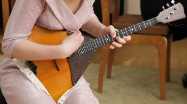 Genç kız elleri Balalaika 'da yakın plan çalıyor, geleneksel Rus telleri halk müziği, müzik okulu eğitimi