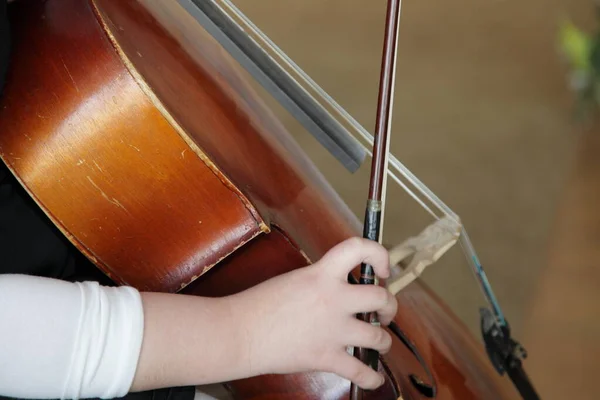 Hand of a cellist girl playing a bow on an old cello close-up, bowed stringed musical instrument in classical music, music school training