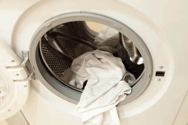 White clothing in front loaded washing machine can with stainless steel rotor and opened door closeup