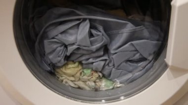 Çamaşır makinesinin önünde durulama yapan bir kıyafet karışımı temiz suyla kapanabilir, ev yıkama...