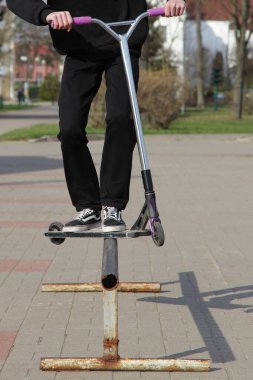 Trick Kickroller scooter kullanan sürücü, metal metro rampasında kayıyor. Yakın çekim ön görüş, aşırı gençlik sporları Avrupa 'da güneşli bir yaz gününde açık havada.