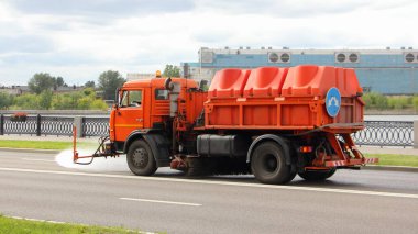 Yeni Rus turuncu sokak temizleyici kamyonu asfalt yolu döktü, Moskova 'da sokak yıkama, güneşli bir yaz gününde belediye hizmetlerinin şehir iyileştirmesi