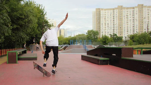 スケートボード上の10代のスケートボーダージャンプトリックモスクワ地区の晴れた夏の日に都市の建物の背景にあるスケートボードのランプコロンセンスカヤ 極端な若者の都市スポーツ屋外 — ストック写真