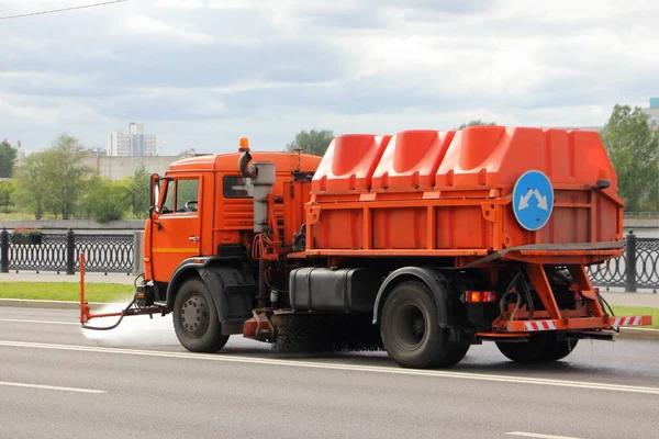 新しいロシアのオレンジの散水機のトラックは 晴れた夏の日に市のサービスによって都市の改善 モスクワでアスファルトの道路 通りの洗浄を注ぐ — ストック写真