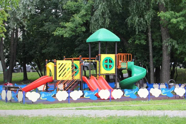 現代のロシアの明るいプラスチック屋外の子供たちは 夏の日に緑の木の背景に遊び場 モスクワの庭で子供の休暇 — ストック写真