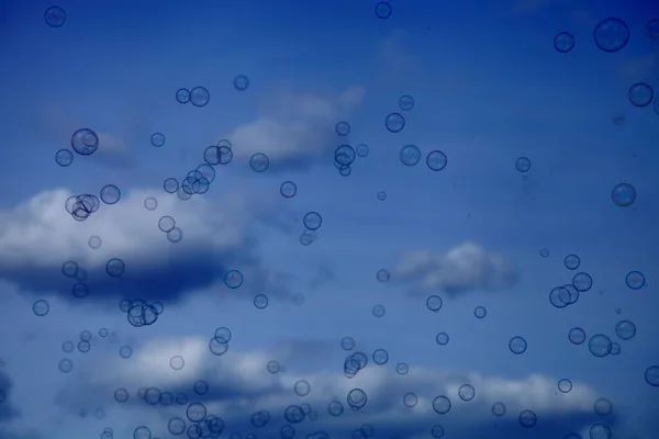 Little soap bubbles against a blue sky with white clouds texture for background