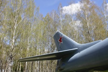 Bir Sovyet turbojet uçağının kuyruk yüzgeci ve dengeleyicisi bir huş ağacının arka planına ve açık mavi gökyüzüne karşı, Rus uzun menzilli havacılık anıtı.