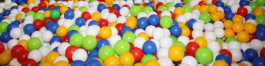 Kuru havuzda bir sürü renkli plastik top: kırmızı, yeşil, mavi, sarı çocuklar parti oyuncakları geniş arka plan dokusu