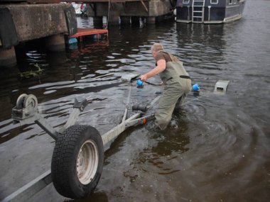 Sürat teknesi denize açıldığında, Avrupalı adam yaz günü limandaki pistteki boş karavana bir tekne koymaya hazırlanıyor.