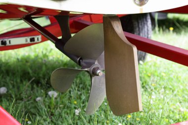Kıç sürücüsü 4 Blades motorlu tekne pervanesi ve direksiyon dümeni sabit bir iç motoru olan bir motorun dümen topçusu ve yaz günü yeşil çimen arka planda tekne römorkunda bir şaft hattı.
