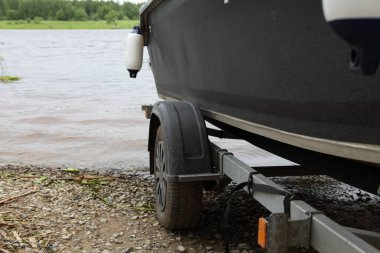 Sürat teknesi suya açılıyor, kıç ve kayık manzaralı şişirilebilir çamurlukla yaz günü nehrin arka planına bakıyor.