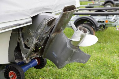 Eski motorlu tekne Transom kıç sürücüsü üç bıçaksız çelik pervaneli ve paslanmaz pervaneli alt ünite ve tuzlu suda kullanıldıktan sonra eğimli silindirli tekne karavan arka planında yakın çekim.