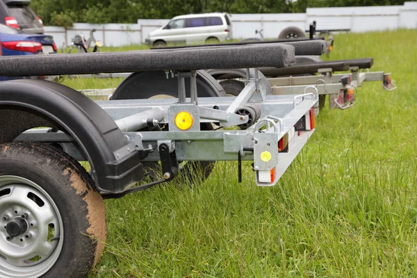 Boat trailers on outdoor grassy parking at summer day, motor boats storage and transportation