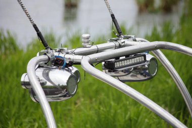 Krom kule teknesi Targa 'yı hoparlörlerle kapatın. Motorlu teknede su kayağı yapmak için bir direk. Yaz günü uyanmak için yeşil çimenlere ve su arka planına karşı, açık deniz sporları aktivitesine karşı.