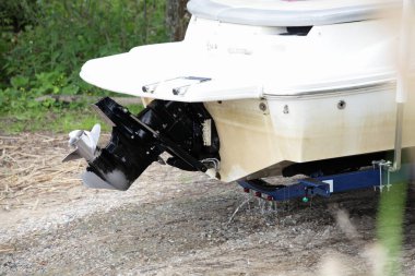 Yaz günü zeminde kayık römorkunda tekne motoru olan güçlü motorlu bir teknenin arka tarafındaki alt birimin sürüşü, su kayakları fırlatılıyor.