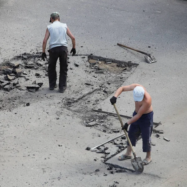 アスファルト敷設 道路便利な修理重い仕事の前に晴れた夏の日にシャベルで古いアスファルトをきれいに2人の道路労働者 — ストック写真