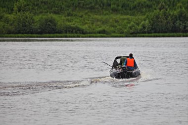 Pruva tenteli şişirilebilir motorlu motor yeşil ağaçlar üzerinde nehirde yüzüyor Rusya 'da Sunnny yaz gününde suda aktif dinlenme