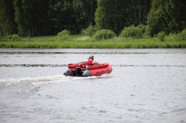 Havada süzülen kırmızı motorlu tekne yaz günü çimenli göl kıyısında, Avrupa 'da açık havada aktif tatil yapıyor.