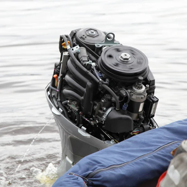Working outboard motor with a rotating flywheel without the hood cap on the transom of the boat, emergency engine start with rope