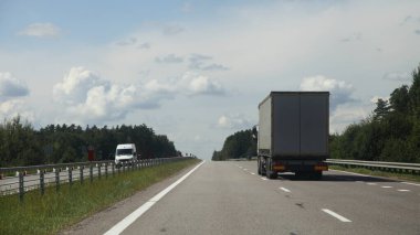 Avrupa ağır kamyon hareketi otoyolda Sunny yaz gününde kırsal yolda mavi gökyüzü ve yeşil orman arka planı, arka manzara, mal taşıma lojistiği