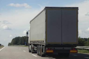 Bir Avrupalı tente kamyonet, arka tarafta Sunny yaz gününde banliyö otobanına yakın çekim sürücüsü. Mavi gökyüzü, beyaz bulutlar, kargo taşımacılığı lojistik lojistiği.