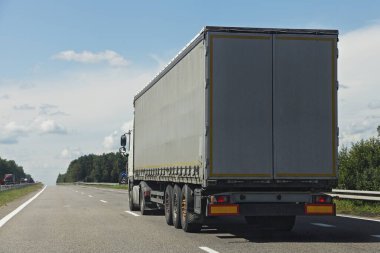 Bir Avrupalı tente kamyonet, arka tarafta Sunny yaz gününde banliyö otobanına yakın görüş sürücüsü. Mavi gökyüzü, beyaz bulutlar, kargo taşımacılığı lojistik lojistiği.