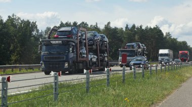 İki katlı otomobil nakliye kamyonları Çin 'in yeni arabalarını Sunny yaz gününde banliyö otoyolunda, ön manzara, dağıtım otomobilleri lojistik, otomobil taşımacılığı