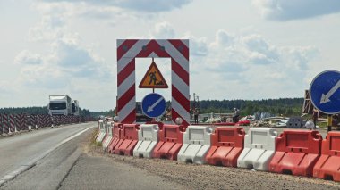 Rus asfalt yol onarım servisi, kırmızı beyaz plastik bloklar, yol ayrımının yönü ve yol çalışması tabelası, yaz günü.