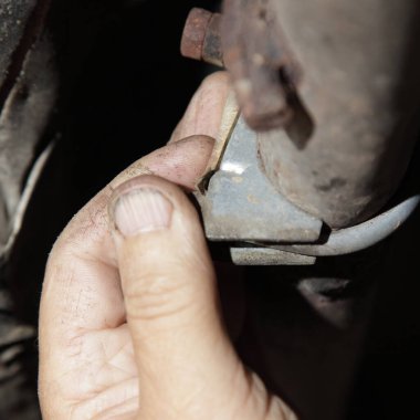 Eski arabanın egzoz sistemini test edin. Bir adamın eli aracın altındaki egzoz borusunu kontrol ediyor.