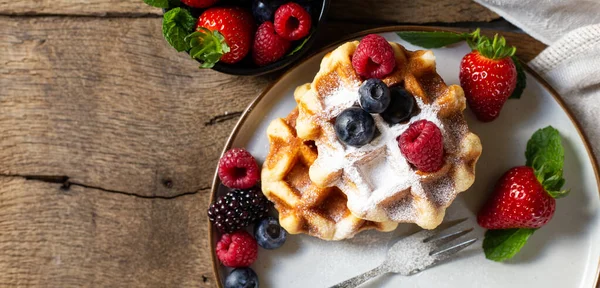 Böğürtlenli ev yapımı tatlılar. Üst Manzara. Belçika waffle 'ı çilek, tabakta yaban mersini ve eski ahşap arka planda tuval. Köy mutfağında kahvaltı.