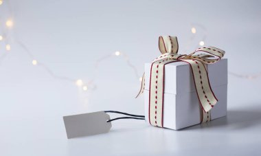 Hediye kutusu, beyaz pastel arka planda hediye etiketli kurdele. Metin için yer