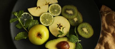 Siyah arkaplan üzerinde turunçgil meyveleri, üst manzara. Yeşil meyveli dramatik mutfak