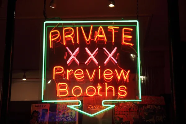 Neon sign of an adult licensed sex shop in a red light district of London at night advertising private preview booths — 图库照片