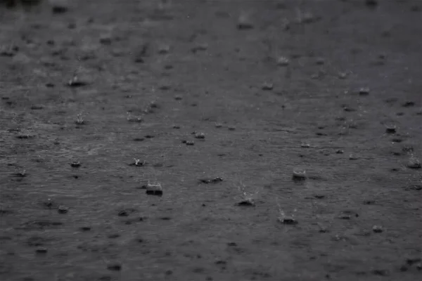 Дождь на темно-серую асфальтовую дорогу — стоковое фото