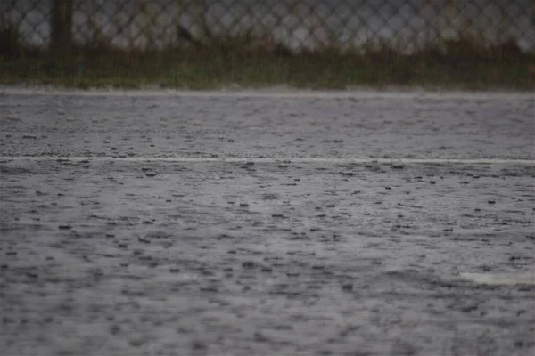 Rain on dark grey a asphalt road and some grass by the roadside — Stock Photo, Image