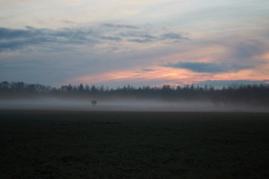 Akşamları sisli ve günbatımlı avcı koltuğuyla manzara