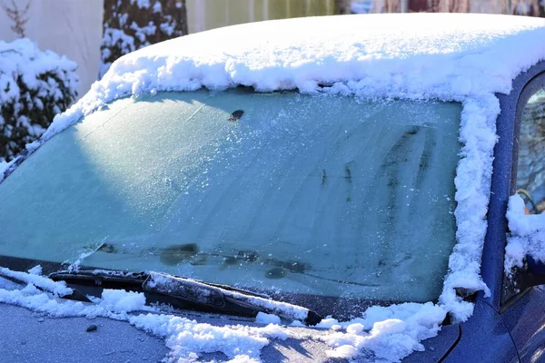 Ice snö på en blå bil med en iskall vindruta i solljuset som en närbild — Stockfoto
