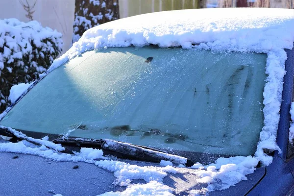 Ice snö på en blå bil med en iskall vindruta i solljuset som en närbild — Stockfoto