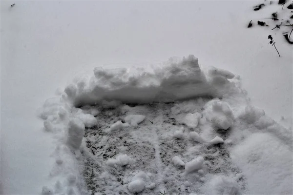 Neve empurrada em uma caminhada lateral durante a queda de neve — Fotografia de Stock