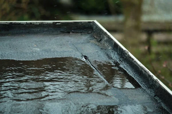 Chuva leve em um telhado plano preto com um pequeno vazamento Fotos De Bancos De Imagens Sem Royalties