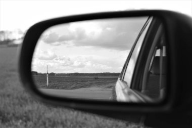 Manzara bir arabanın dış aynasına tek renkli bir görüntü olarak yansıtılır.