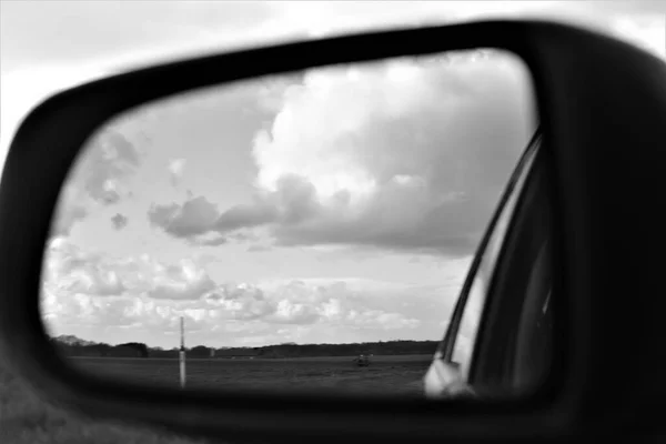 The landscape is reflected in the exterior mirror of a car as a monochron image — Stock Photo, Image