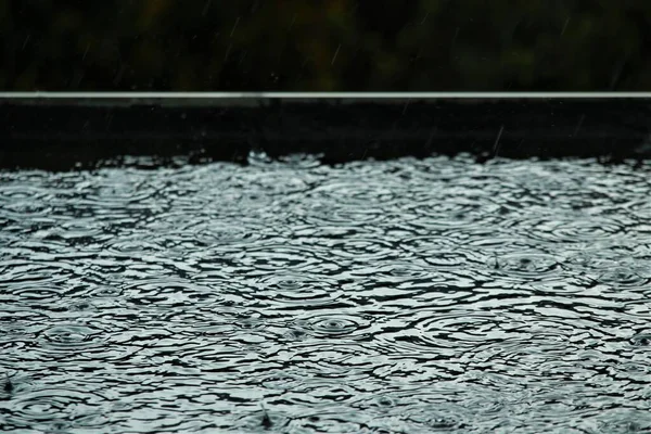 Rain is makes circles on a black flat roof