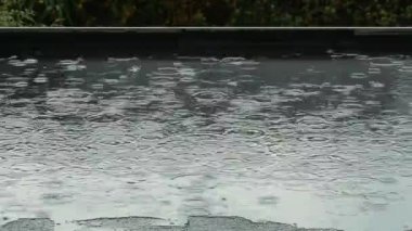 Siyah, düz bir çatıda yağmur yağıyor.